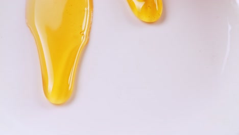 liquid and fresh honey dripping to the white background. healthy organic thick honey closeup, sweet honey dessert 4k. slow motion