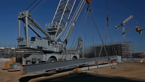 large crawler crane lifting a steel beam at a construction site