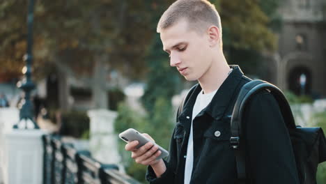 young student using mobile phone outdoors.