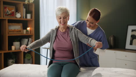 senior woman exercising with resistance band with assistance from therapist