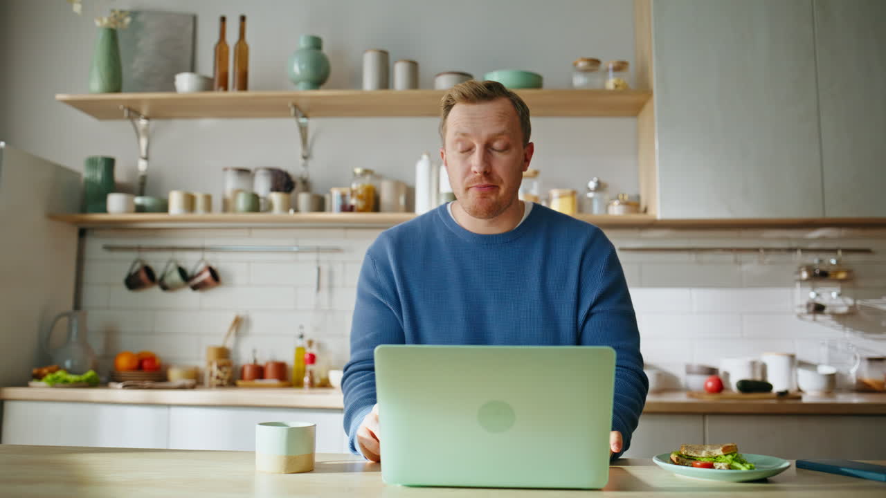 Eating man video calling home morning closeup. Smiling startuper biting sandwich