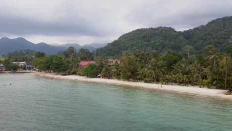 Vista-Aérea-A-Lo-Largo-De-La-Costa-De-La-Playa-De-Kai-Bae-Con-Un-Paisaje-De-Bosque-Tropical-En-El-Fondo