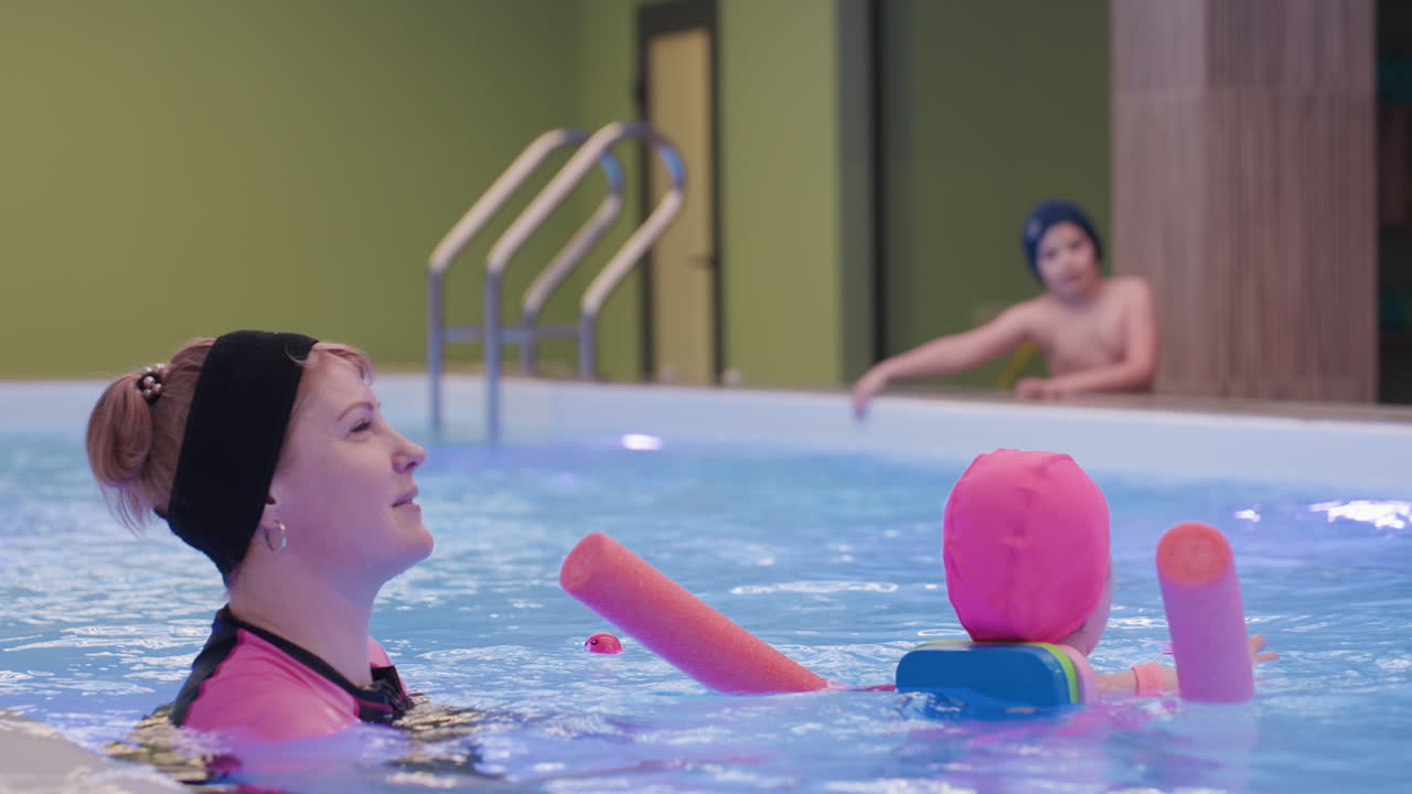 Clear view of clean water with white lad in background preparing to swim, bright ripples, blue pool tiles, soft daylight, calm scene, anticipation before dive, crisp reflections across surface