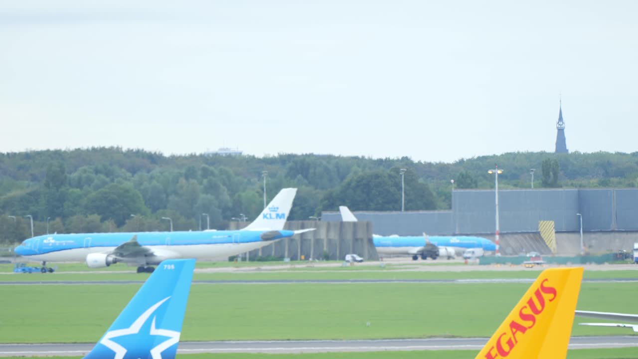 다른 비행기가 이륙하는 동안 암스테르담 스키폴을 향해 탈출하는 택시를 지나가는 큰 klm 에어버스