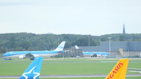 un gran airbus klm se mueve sobre un taxi en fuga hacia el aeropuerto de ámsterdam schiphol mientras otro avión despega