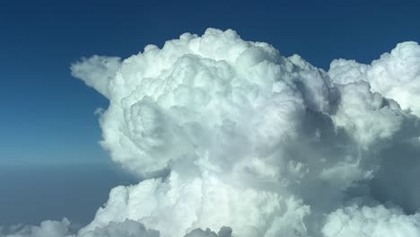 closeup view of the top of a huge and vilolent cumulonimbus storm cloud shot from a jet cabin flying at 12000m high