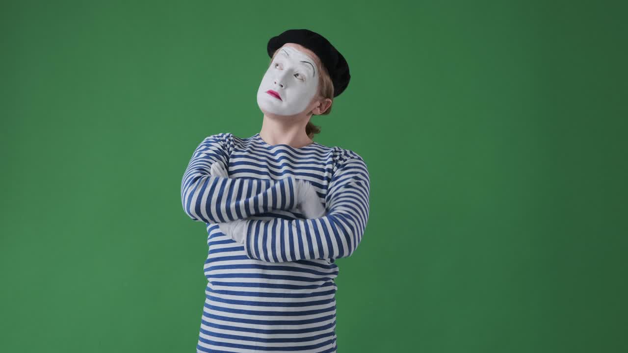 참을성 없는 미미 아티스트가 녹색 배경 위에서 기다리는 동안 시간을 확인합니다.