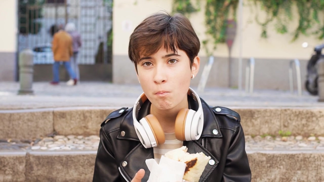 Una giovane donna che si gode felicemente uno spuntino gustoso mentre si rilassa in un suggestivo ambiente urbano