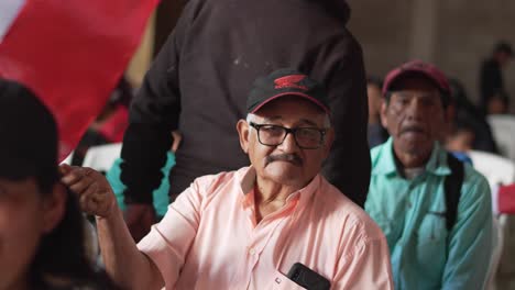 older man holding a peruvian flag at a public gathering