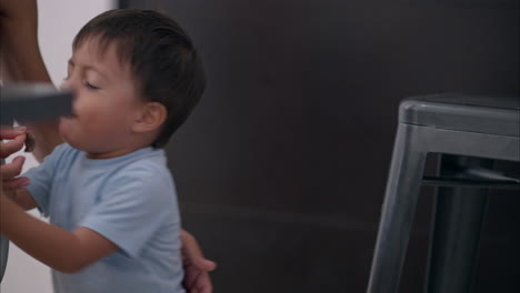 Cute-latin-toddler-kid-baby-boy-playing-with-his-mom-laughing-and-having-fun-while-eating-some-snacks-near-the-table