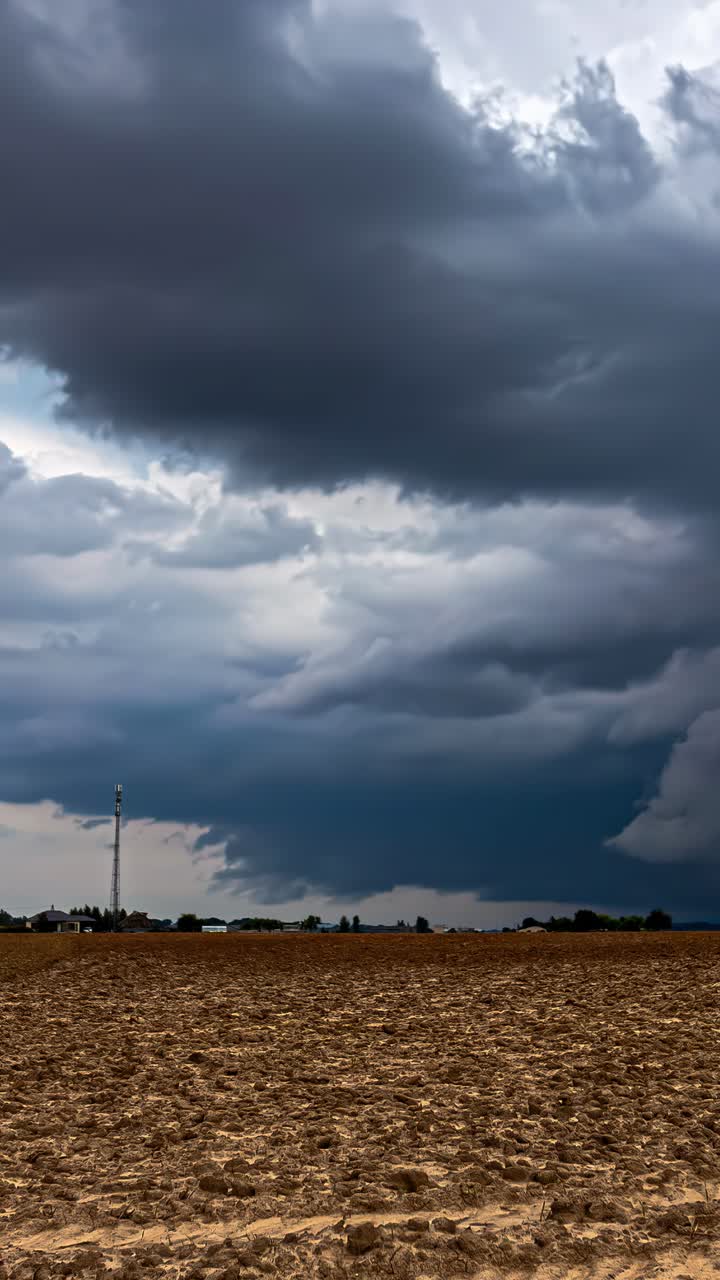 Tornado clouds swirling above dry ground and radio tower, dramatic storm weather, vertical