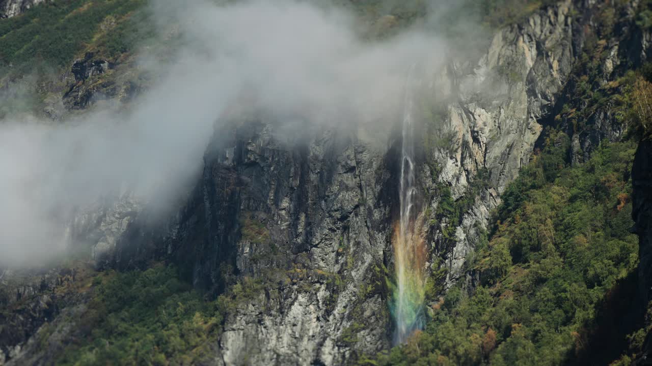 geiranger에 있는 gerdfossen 폭포는 바위 절벽 아래로 흐르고, 빛은 안개 속에서 다채로운 무지개를 아니다.