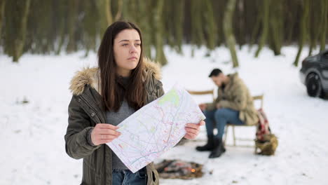 mujer caucásica comprobando el mapa en busca de direcciones en un bosque nevado.