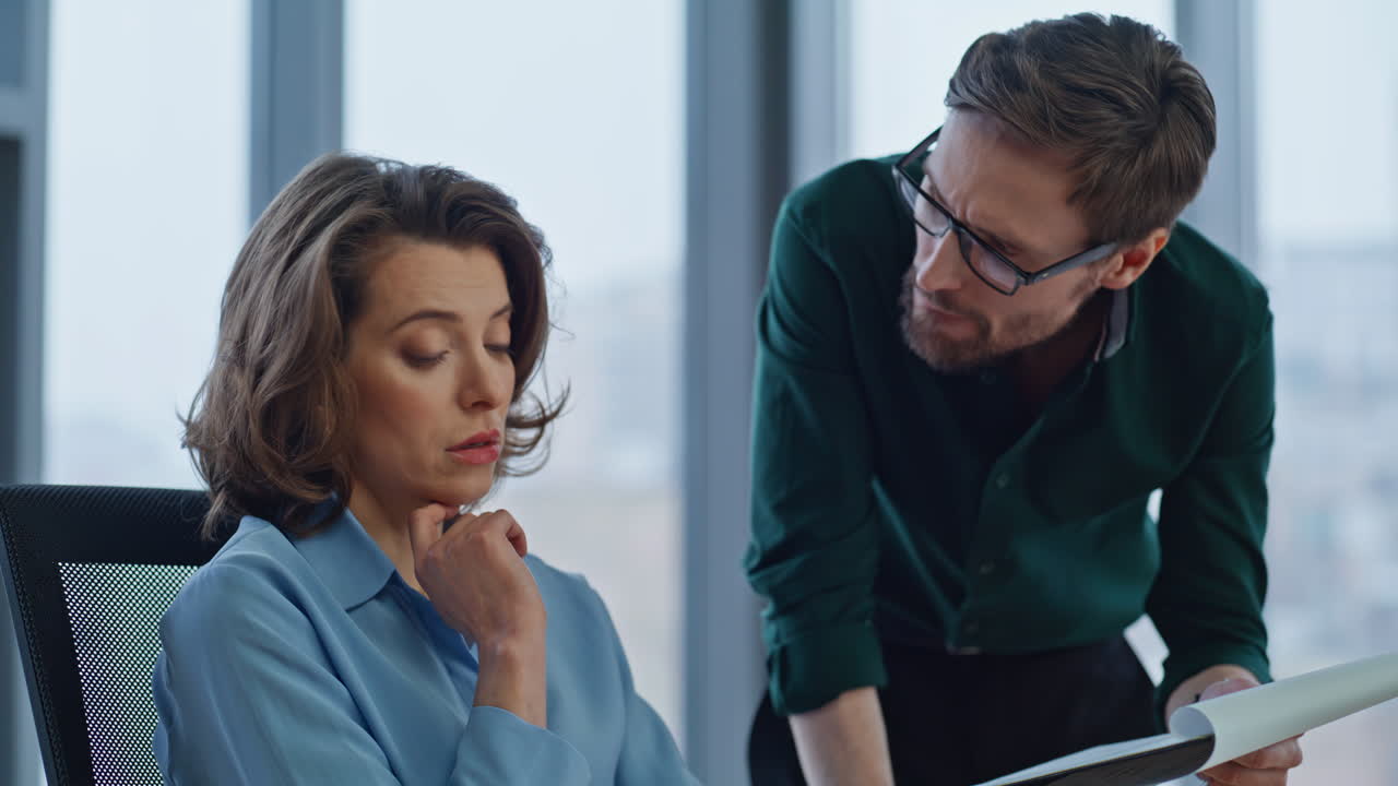 Serious boss asking manager about report data in company workspace closeup