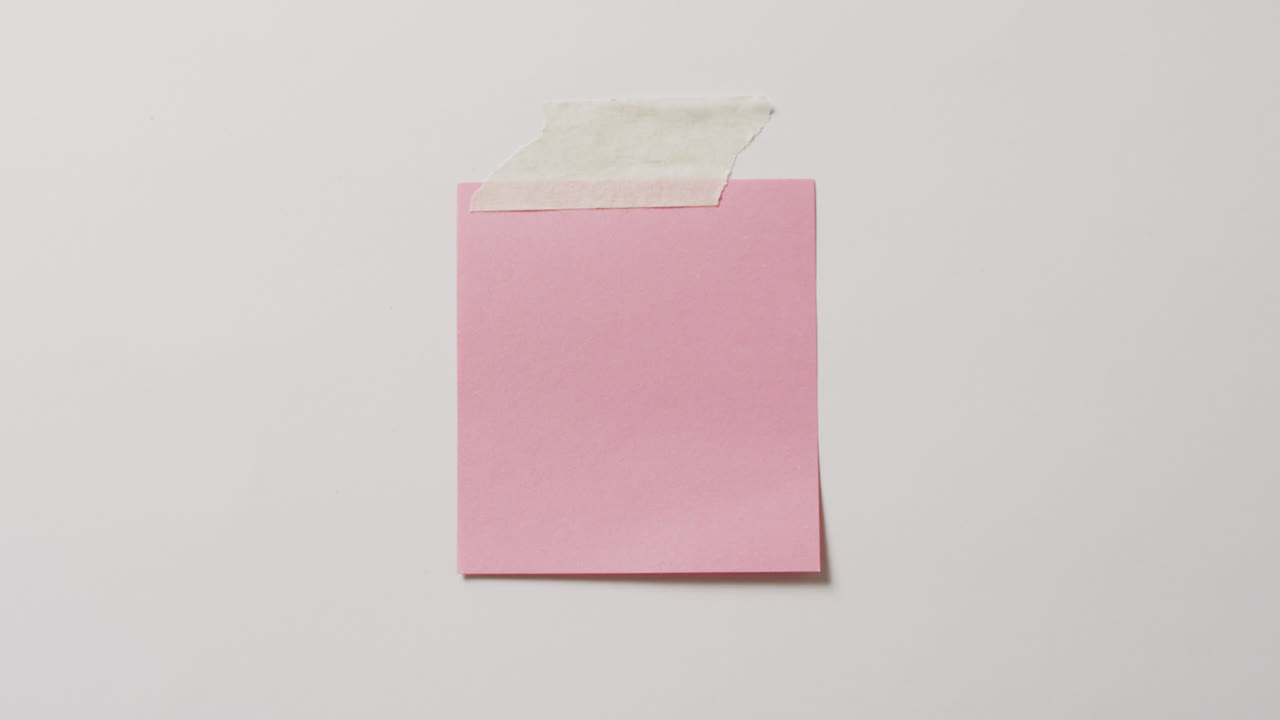 ⁇ 색 배경에 테이프를 붙인 복사 공간과 함께 분홍색 메모 메모의 클로즈업 비디오