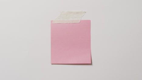 video of close up of pink memo note with copy space taped to white background