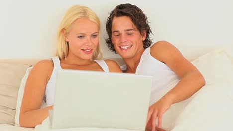Cute-couple-sitting-in-bed-with-a-laptop