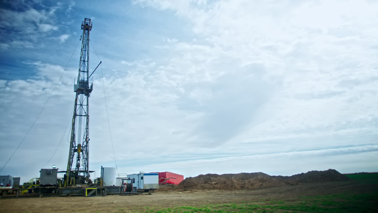 The site for oil or gas production. High metal tower for drilling the minerals. Low angle view.