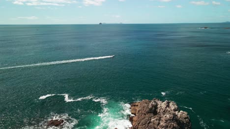 Boat-passing-along-the-coastline-of-the-Coromandel-Peninsula,-New-Zealand