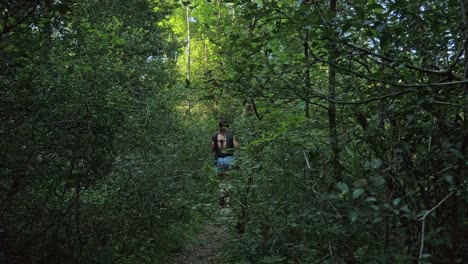 una hembra adulta y su perro se abren camino entre los árboles de un bosque