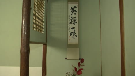 tatejiku calligraphy scroll and ikebana flower arrangement in tokonoma alcove of japanese tea house