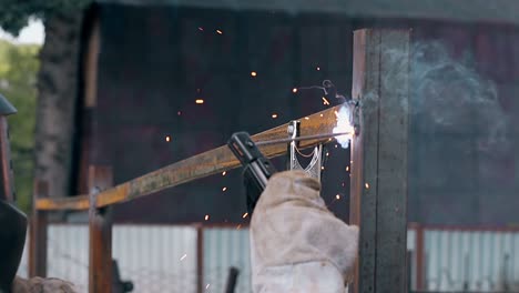 slow motion closeup builder welds plank to fence at house