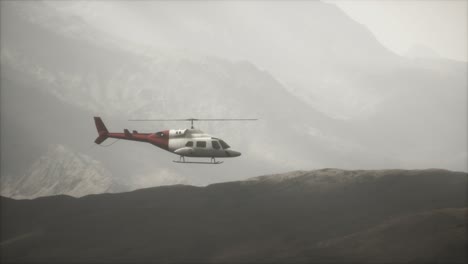 helicóptero volando en cámara lenta extrema cerca de las montañas con niebla