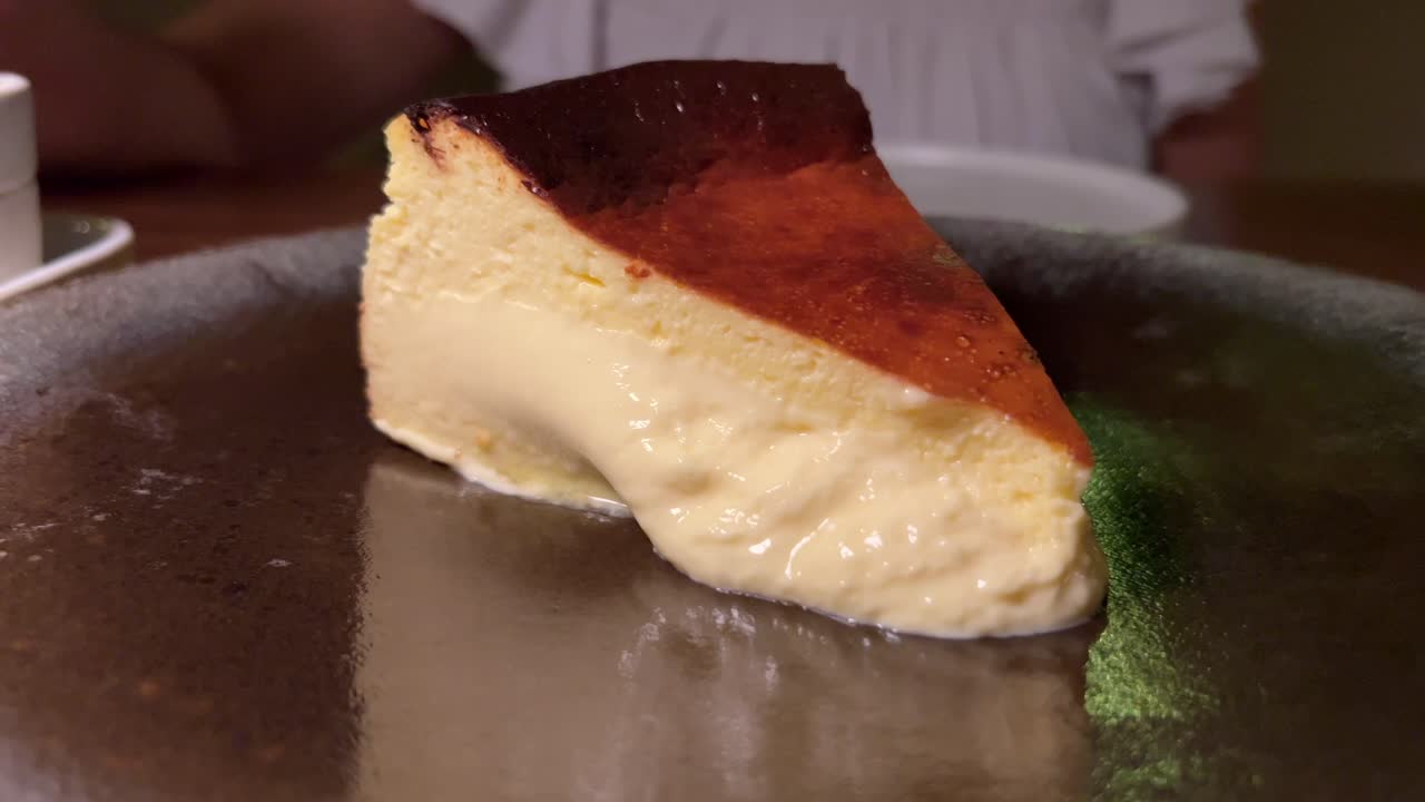 Cheesecake basca bruciata tradizionale spagnola, dolce cremoso su un piatto in un ristorante, ripresa in 4K.
