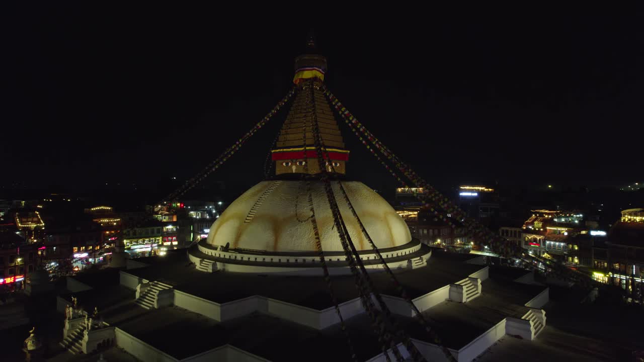 A nighttime drone view showcasing Boudhanath Stupa glowing across Kathmandu. The world heritage site stands bright, its spiritual significance and serene atmosphere in the city's nightscape