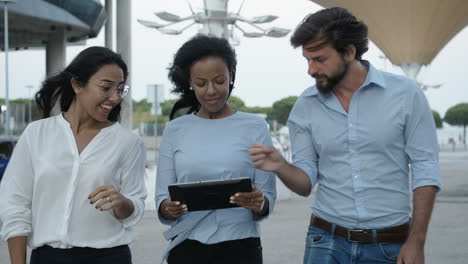 trois collègues marchant avec une tablette et parlant à l'extérieur par une journée venteuse