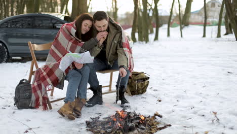 caucasian couple camping in a snowed forest.