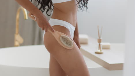woman using body brush in a bathroom
