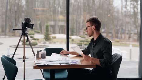 side view of a young blogger reviewing papers and preparing to record a video