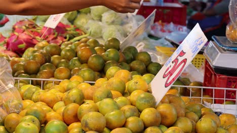 manos recogiendo naranjas de un puesto de mercado