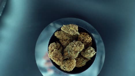 una grúa cinematográfica de arriba hacia abajo detallada suave zoom out movimiento tiro de una planta de cannabis, cepas híbridas de naranja, tipo indica, flor de marihuana, cámara lenta 120 fps, estudio led luces, soporte giratorio
