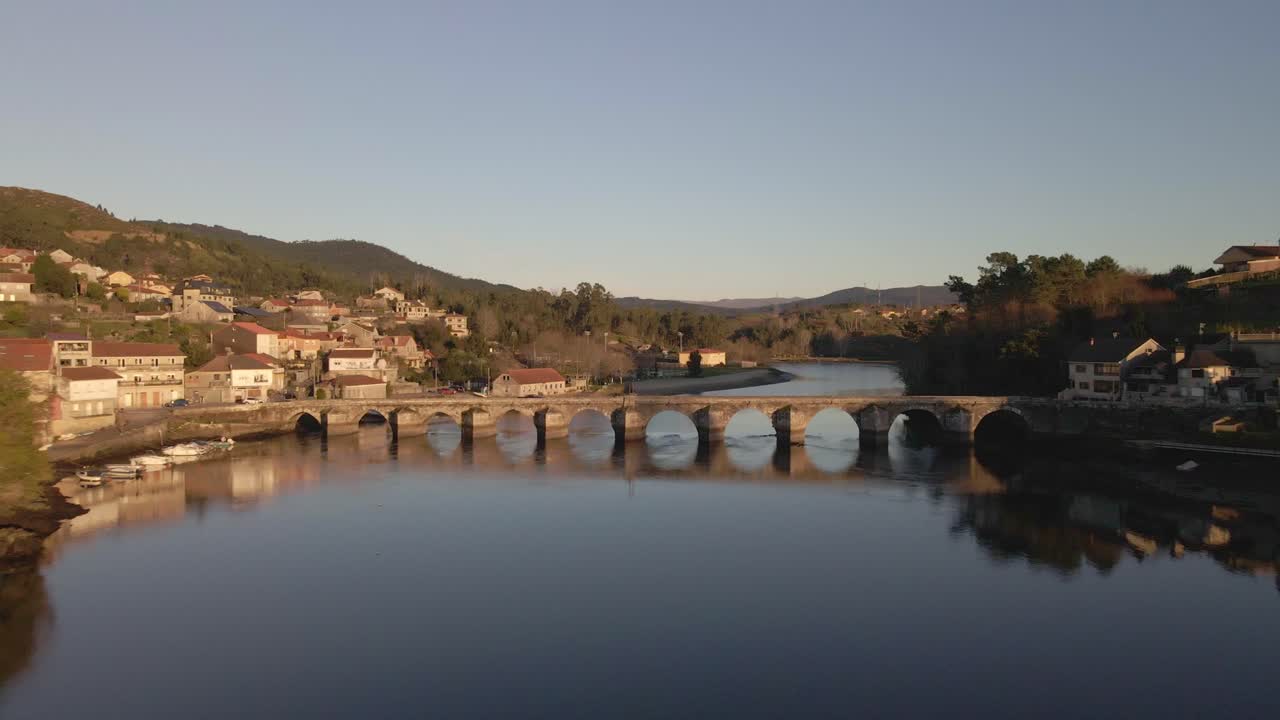 Una splendida ripresa di un fiume dove un ponte è visibile al centro e il fiume è circondato da una collina.