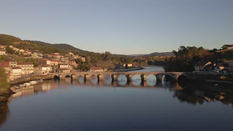 Es-Wird-Eine-Schöne-Aufnahme-Eines-Flusses-Gemacht,-Bei-Der-Eine-Brücke-In-Der-Mitte-Des-Flusses-Zu-Sehen-Ist-Und-Der-Fluss-Von-Einem-Hügel-Umgeben-Ist