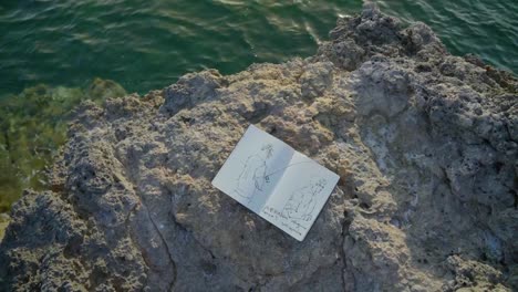 sketchbook on the shoreline, artistic sketchbook placed at the top of the rocks near the sea