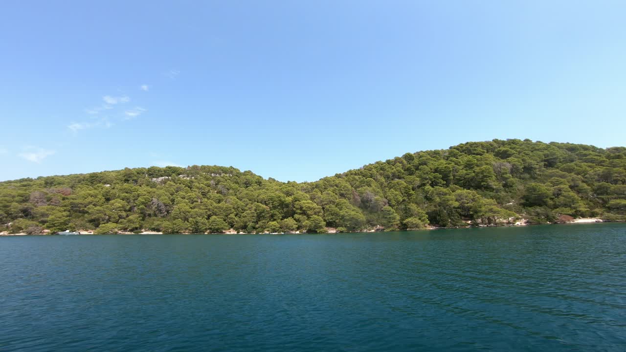 푸른 물과 푸른 소나무 숲 위로 움직이는 배에서 바라본 풍경