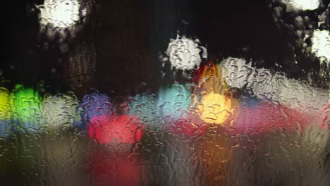 night city traffic through the wet car window. smooth defocusing of the lens. autumn evening in the big city concept. uhd, 4k