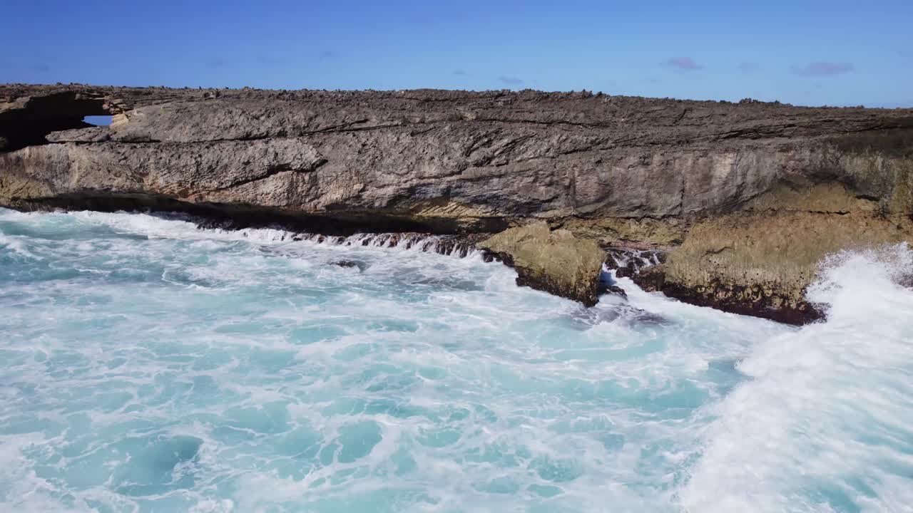 Powerful Ocean Waves Crashing Against a Rocky Coastline with a Natural Arch