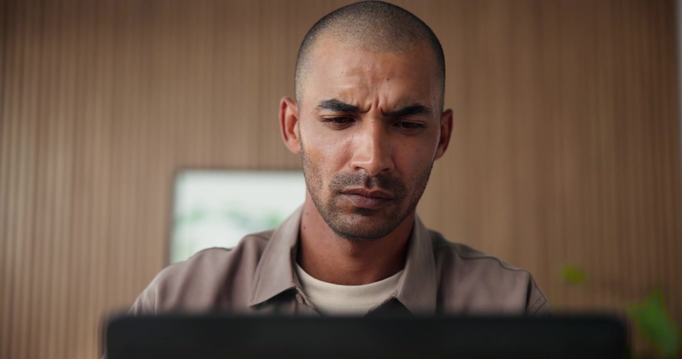 Ein konzentrierter Mann arbeitet an einem Laptop im modernen Büro