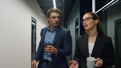 two colleagues talking office on break. friendly team managers walking hallway