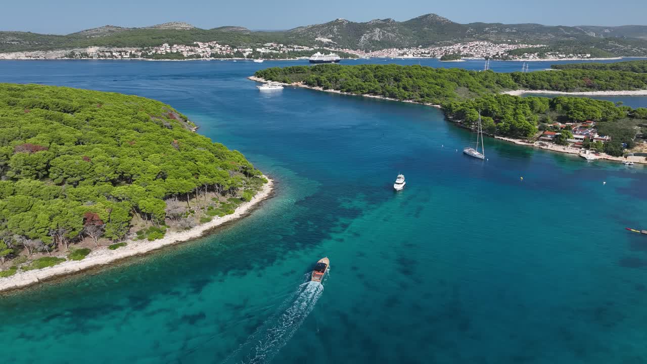 Boats on turquoise water by islands in sunny Croatia, wide aerial pan