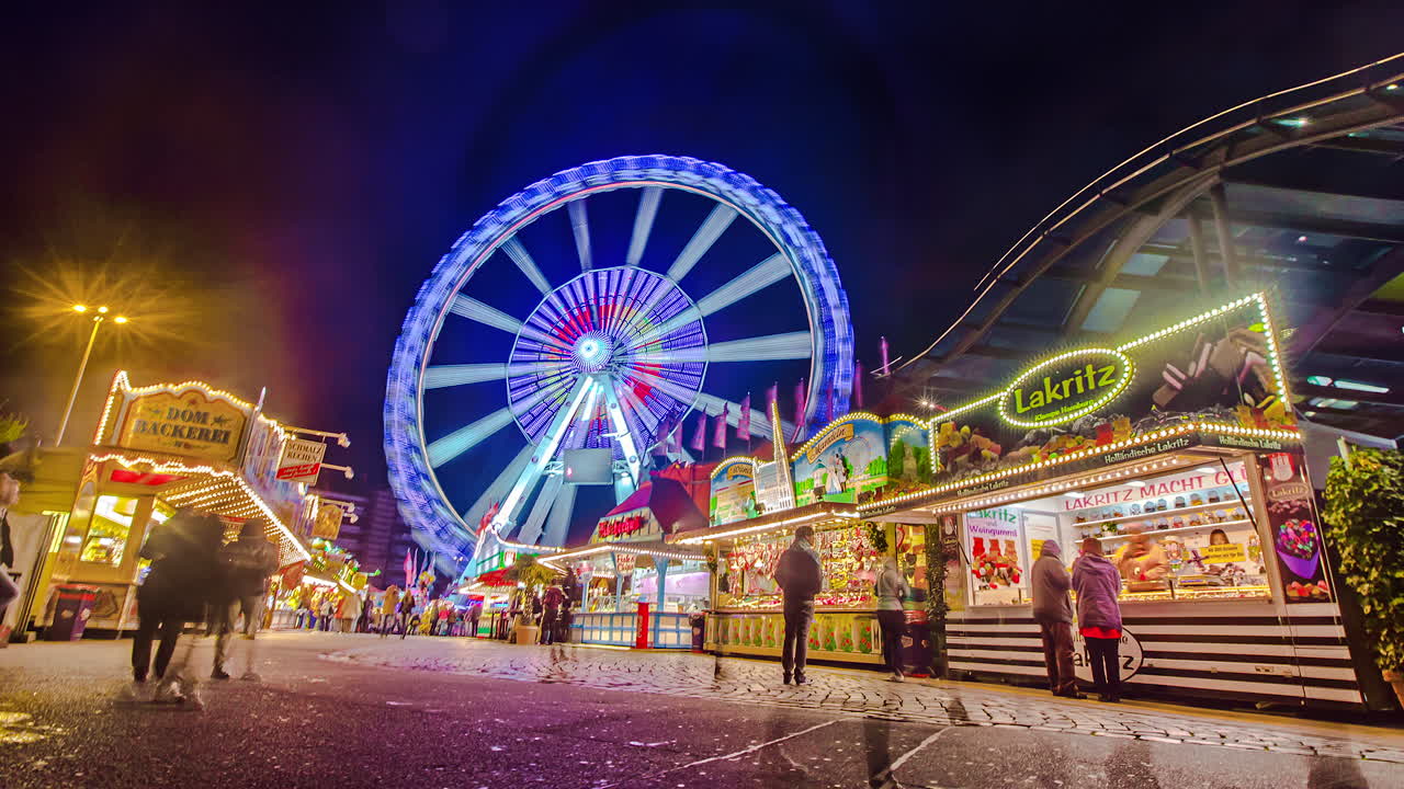 Time lapse shot of people walking over german amusement park with lighting ferris wheel in background