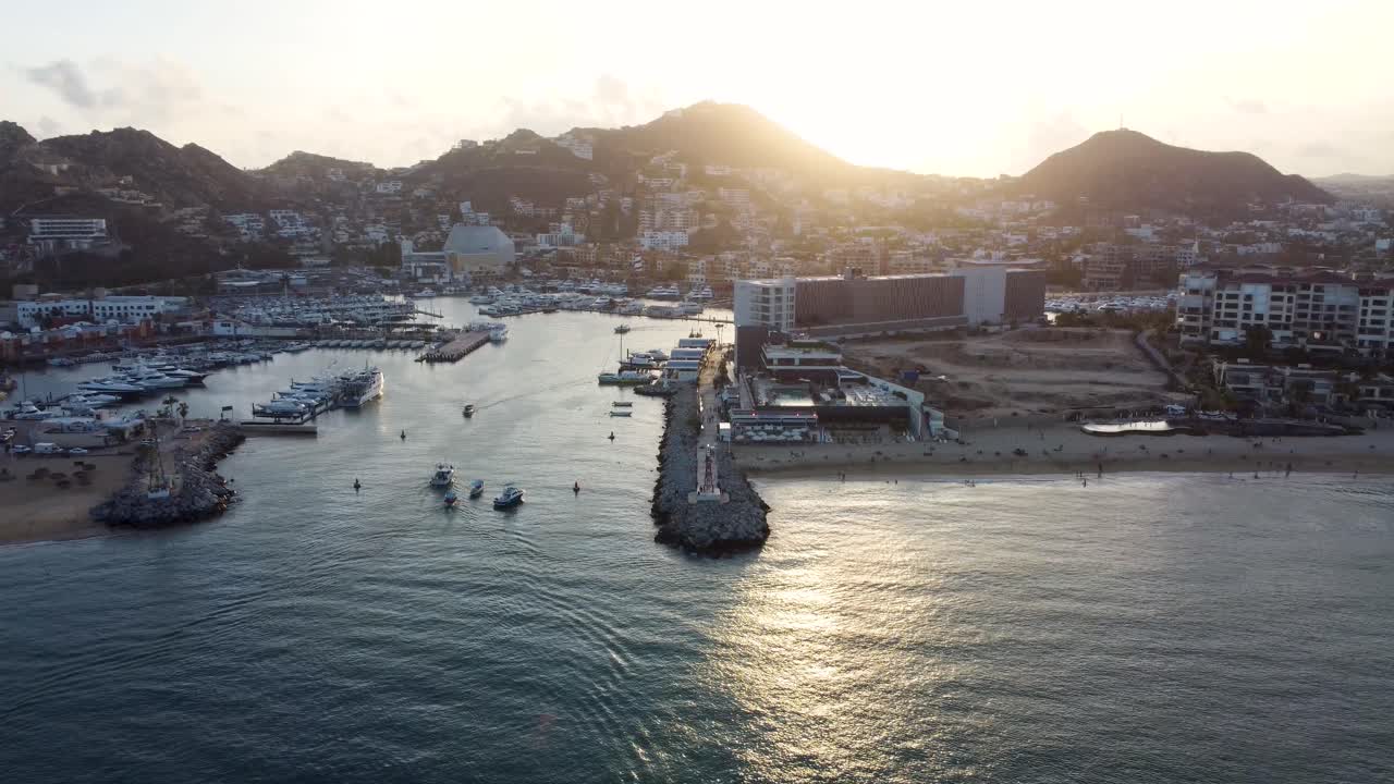 물속의 보트와 해변의 사람들이 있는 일몰의 정박지