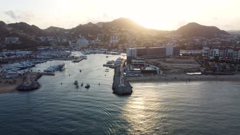 marina at sunset with boats in the water and people on the beach