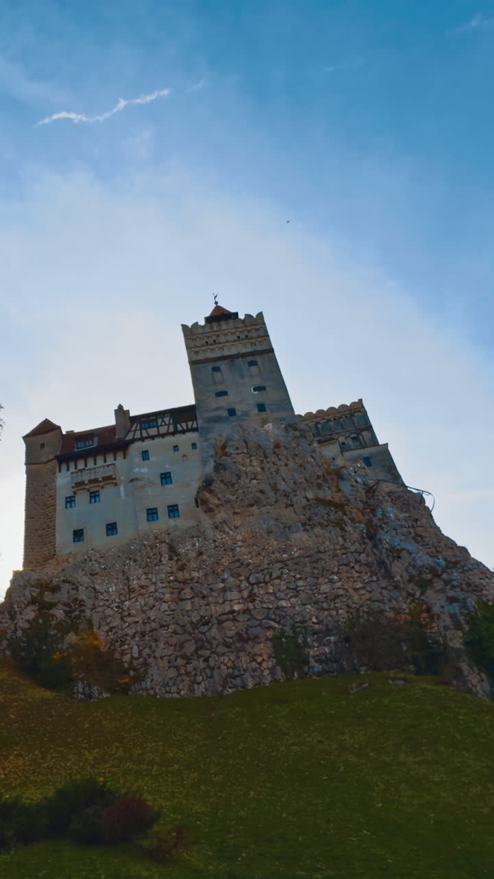 Old Dracula castle towering on the hill in Brasov, Romania. Beautiful bright colorful trees surrounding the building. Vertical video