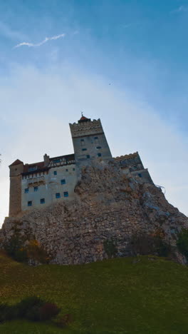 old dracula castle towering on the hill in brasov, romania. beautiful bright colorful trees surrounding the building. vertical video
