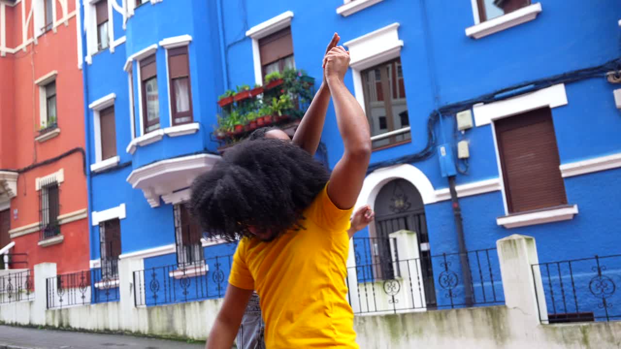 Two People Dancing in Front of Colorful Buildings